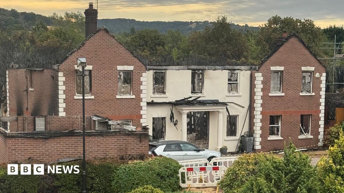 Photo: bbc.co.uk A large building with white pillars, significantly destroyed by fire. The roof has burnt away and much of the back of the