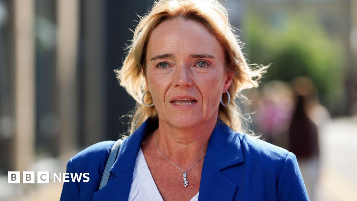 A woman with blonde hair in a blue jacket and white shirt. 