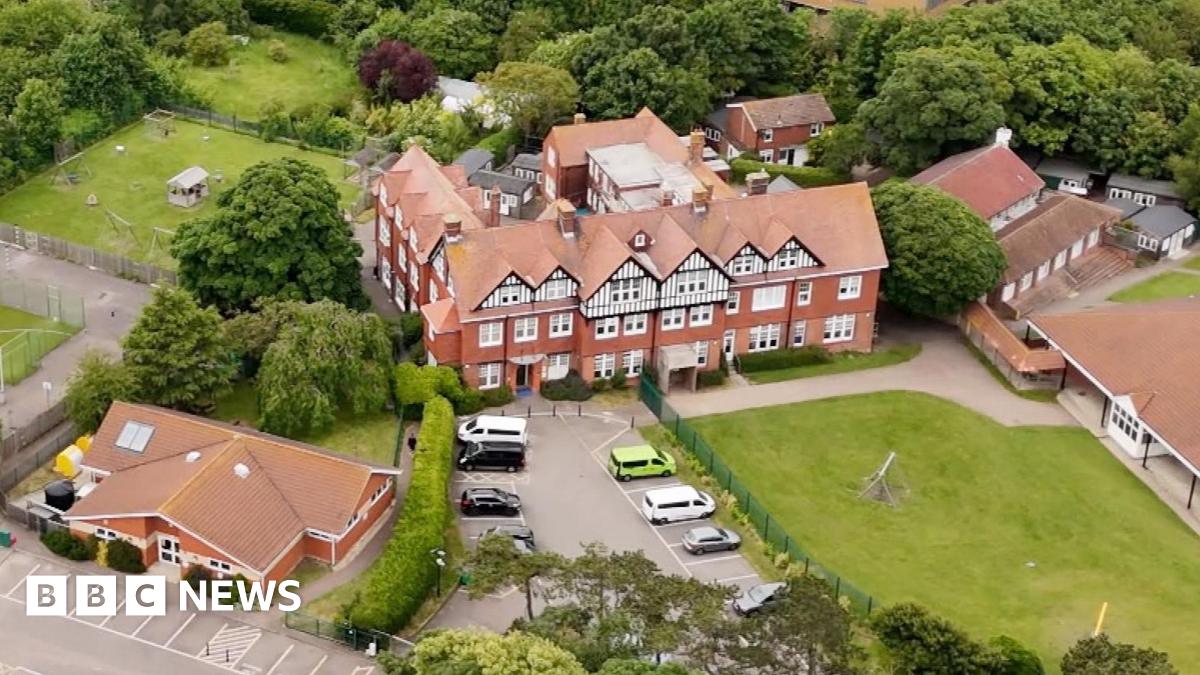 An aerial view of Bradstow School showing a large school building and its surrounding grounds. There are a number of smaller nearby buildings.