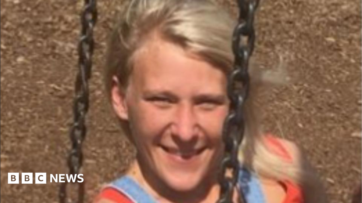 A smiling Charlotte Tetley relaxes on a swing, her blonde hair blowing in the wind