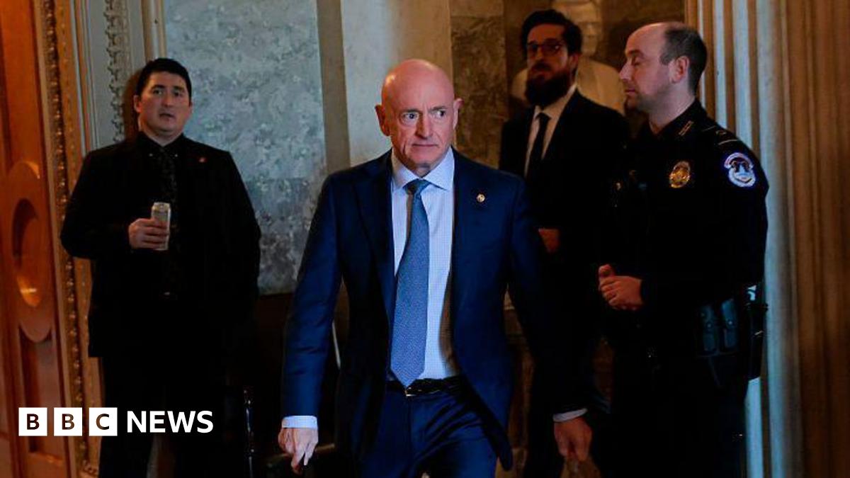 US Senator Mark Kelly seen walking through the halls of Congress, flanked by police and staff