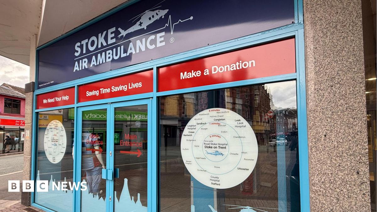 The front of a charity building that has glass doors and windows and red and blue signage. It says "Stoke Air ambulance"