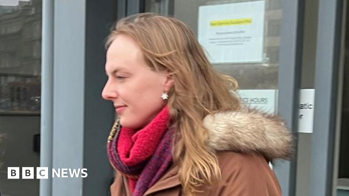 Dr Beth Upton - a transgender woman with long blonde hair, a red scarf and a brown jacket - leaves a building