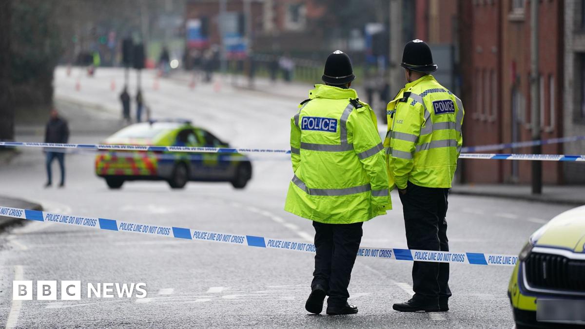 Two officers stand with their backs to the camera next to police tape with a police car in the road in the background in Leicester city centre on Wednesday morning. 