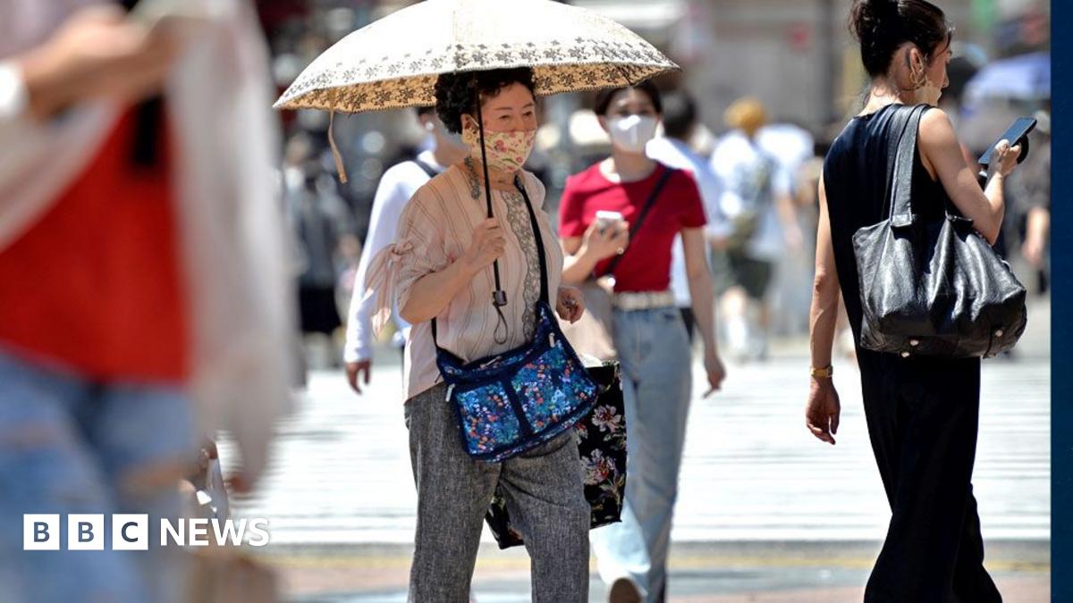 An old person walks on the street using an umbrella to protect herself from the sun on June 27, 2022, in Tokyo's popular Shibuya district in Tokyo, Japan