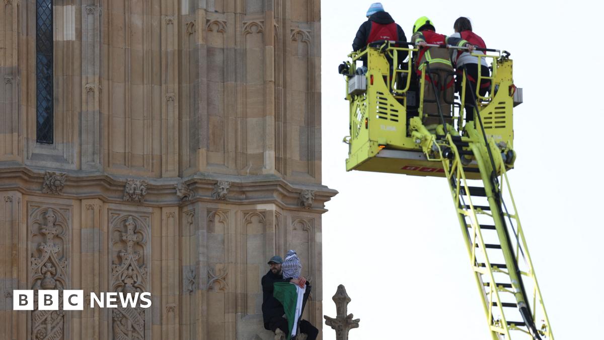 A man with a Palestinian flag reacts next to first responders as he stands on the Elizabeth Tower.