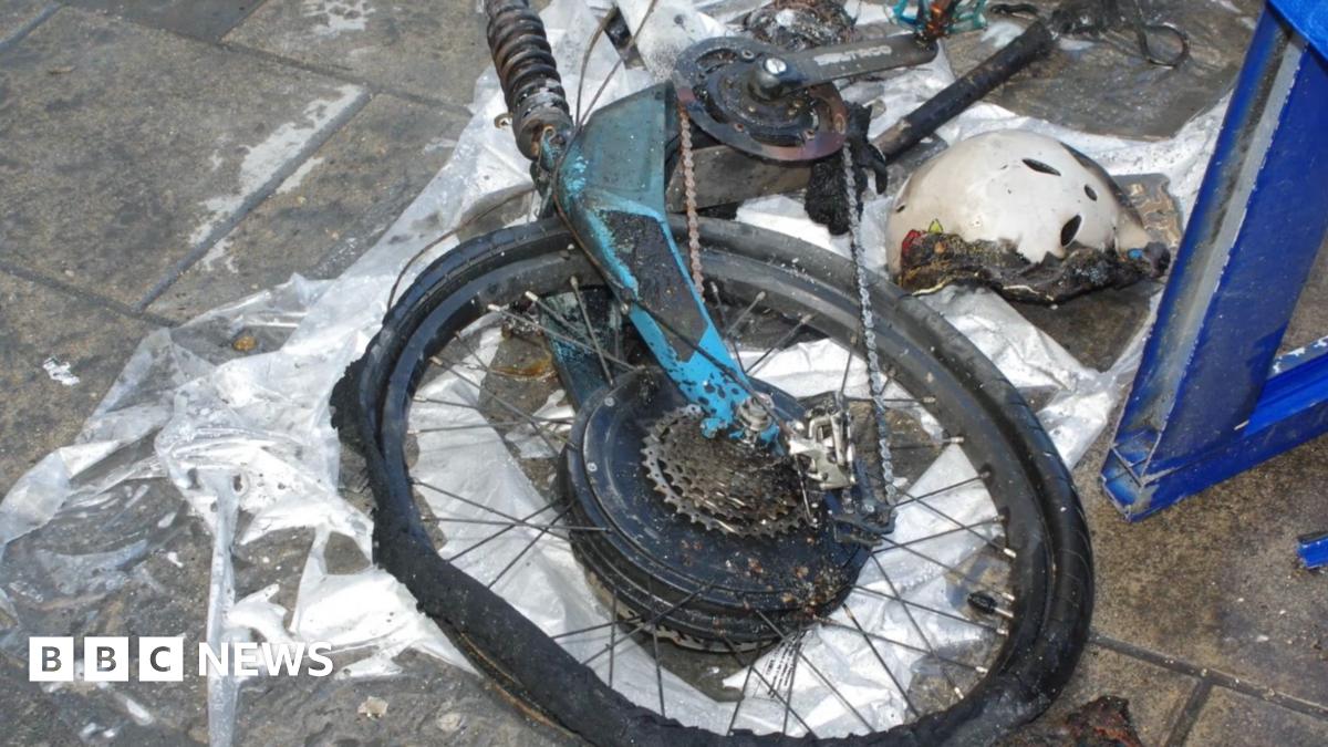 An image of a fire-damaged bike laying on a concrete floor