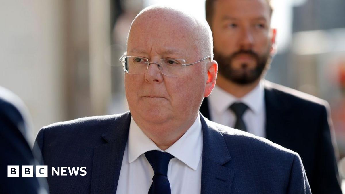 Peter Murrell, who is bald with glasses, in a close-up shot while walking outside. He is wearing a business suit 