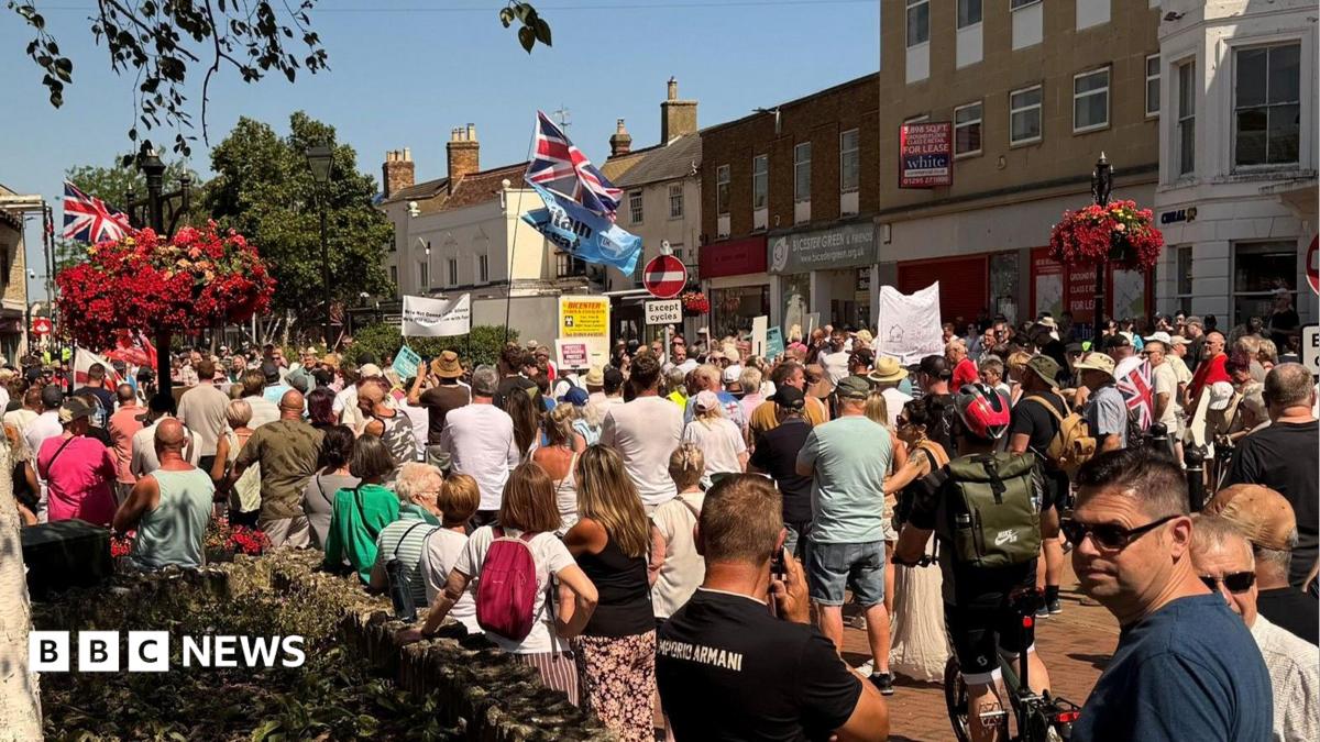 A crowd of people in a high street, with several banners and union flags flying