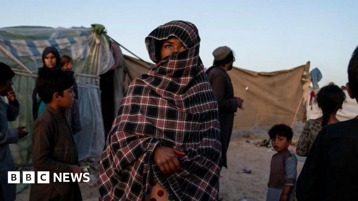 A female refugee covered with a veil, though her eyes and nose can still be seen, stands at a refugee camp in Afghanistan 