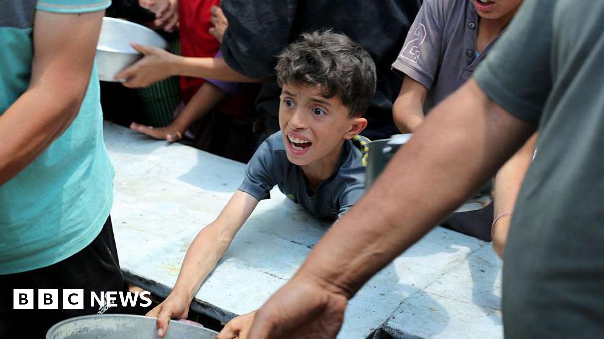 Palestinians gather for a hot meal at a food distribution point in the Nuseirat camp for refugees in the central Gaza Strip on May 21, 2025. Gazans waited desperately for vital supplies on May 21 after Israel said it let in dozens of UN trucks but face...