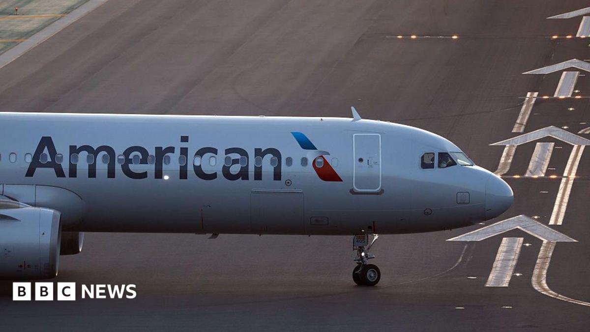 The front of an air plane with the American logo on a runway