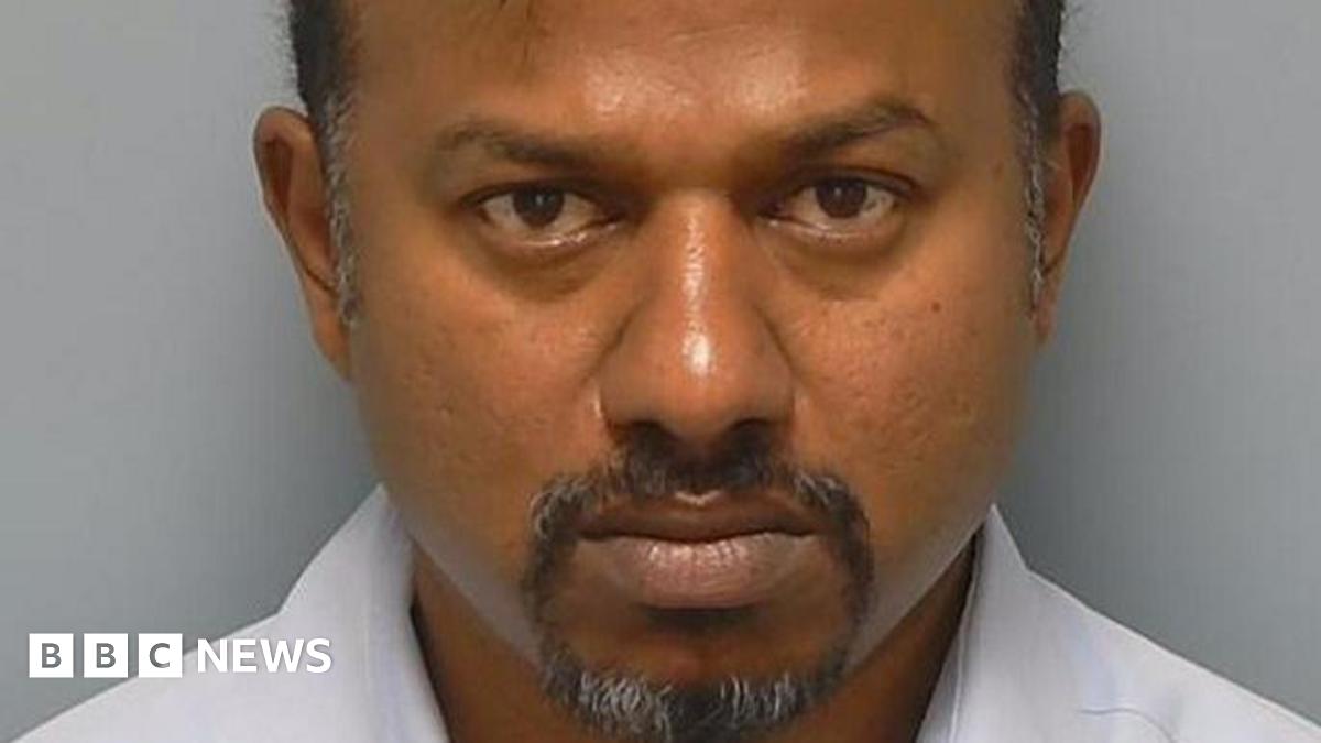 A custody photo of Mohan Babu who has greying hair and goatee beard