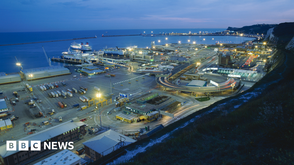 A view of the port of Dover at dusk from the White Cliffs above the port, showing ferries and traffic.