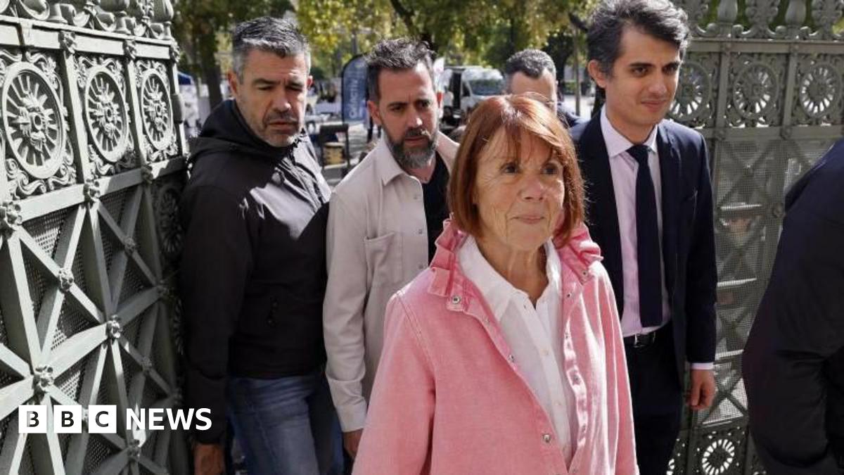 A woman in a pink top flanked by men enters court in the southern city of Nîmes