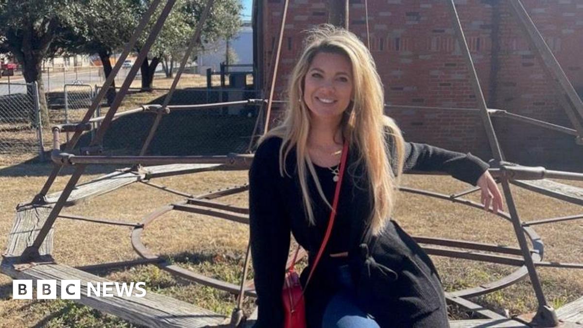 Adrienne Martin sits on a bench outside while wearing a black sweater