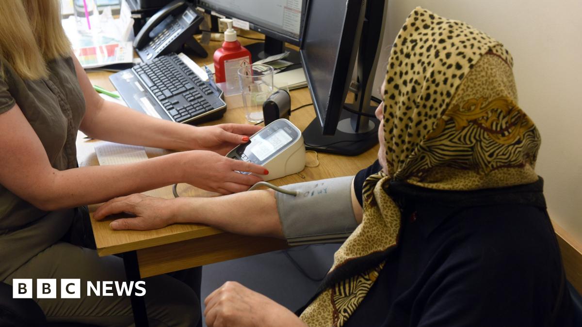 A GP takes the blood pressure of a patient 