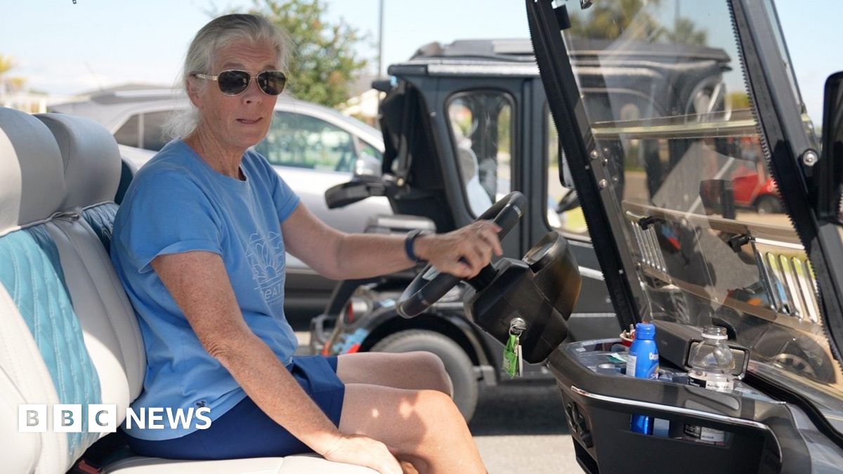 Maddy Bacher in a golf cart wearing sunglasses and a blue tank-top