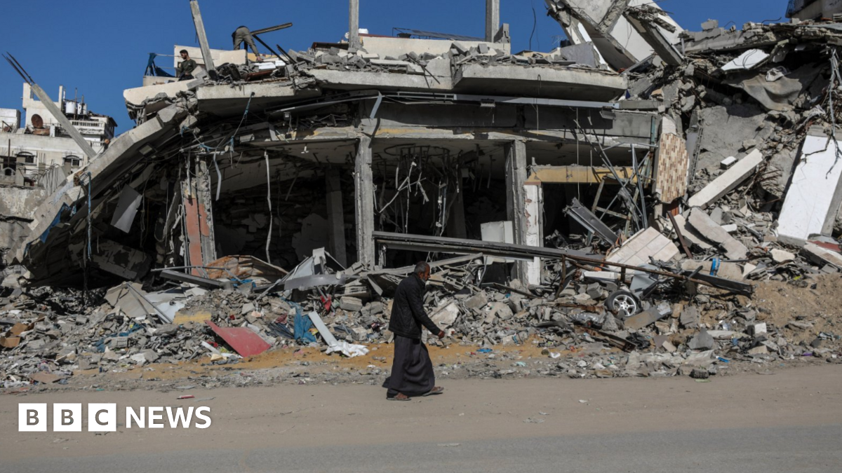 An elderly Palestinian man walks past a destroyed building in Gaza City