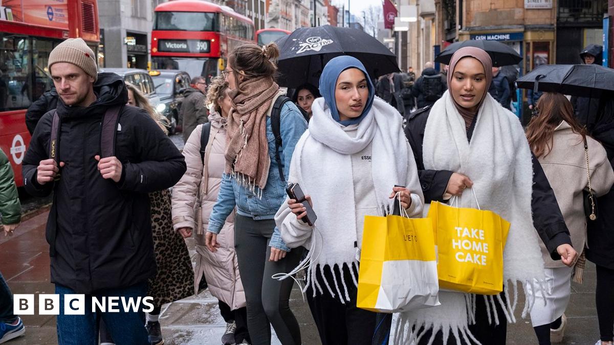 People with shopping bags walk down Oxford Street on a sunny day in late January