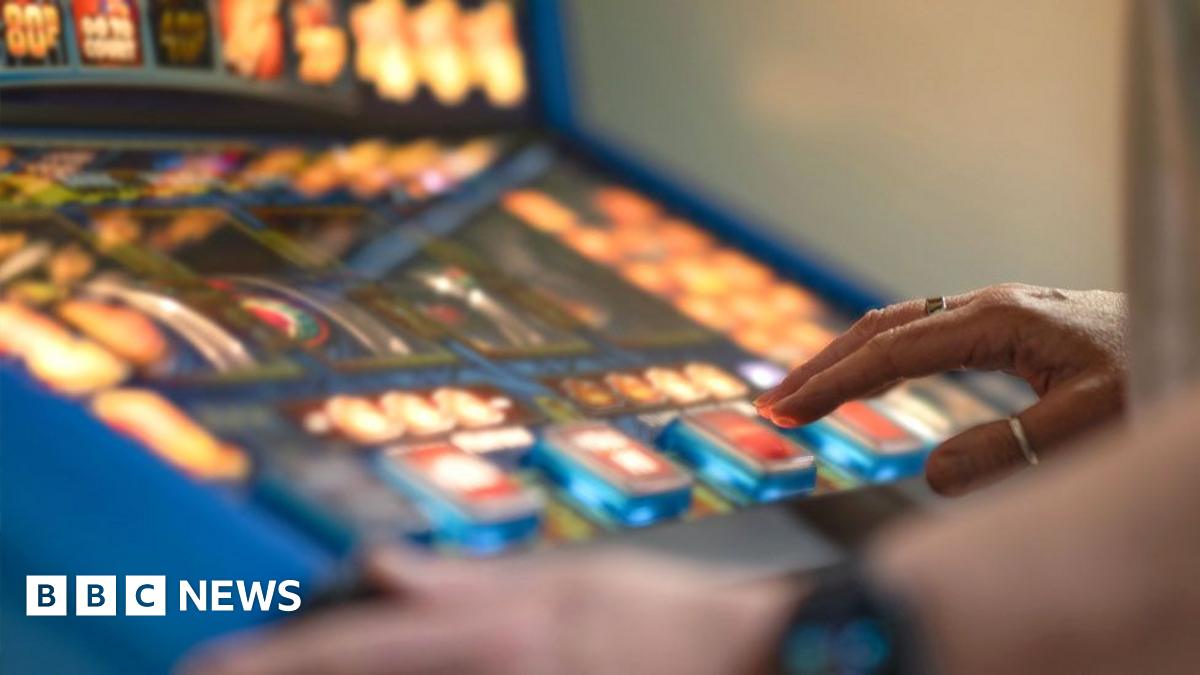 A person presses buttons on a colourful slot machine