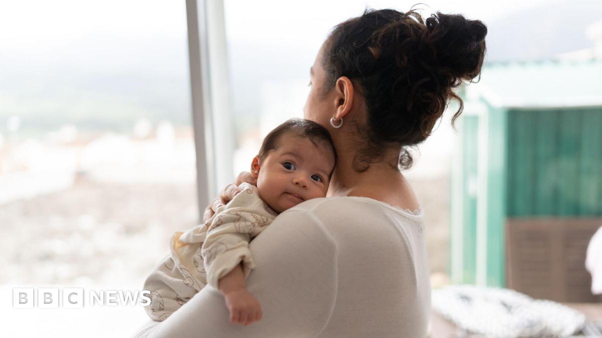 A mother holds her baby upright to rest on her shoulder