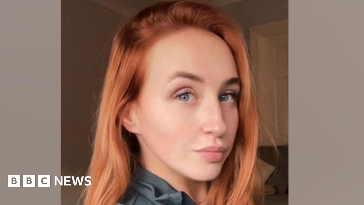 A woman with red hair and blue eyes smiling. 