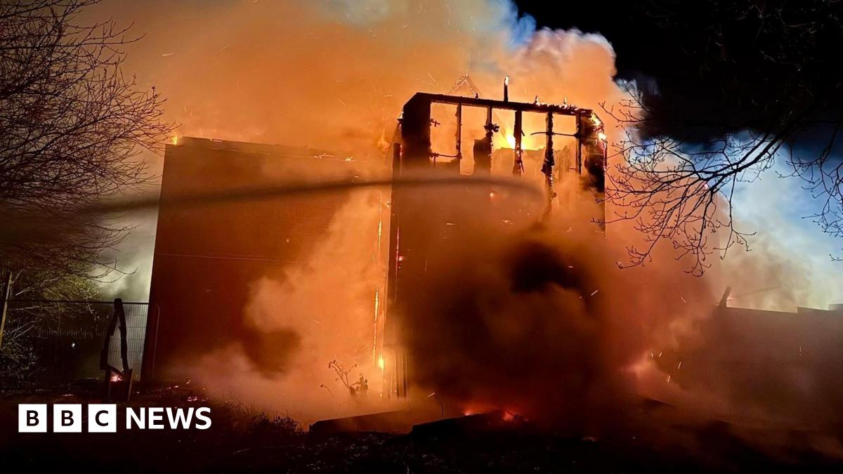 A part of the hotel, which can be seen badly damaged, is engulfed in smoke and a bright orange glow from the flames of the fire.