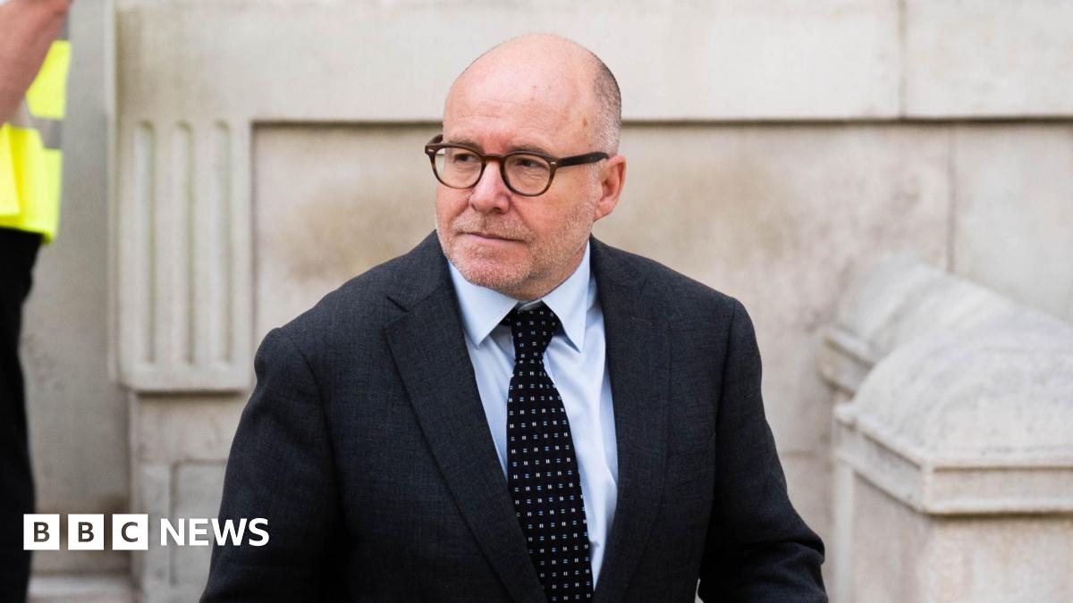 Attorney General Lord Richard Hermer leaves the Cabinet Office on Whitehall. He is wearing a dark suit and dark, spotted tie.