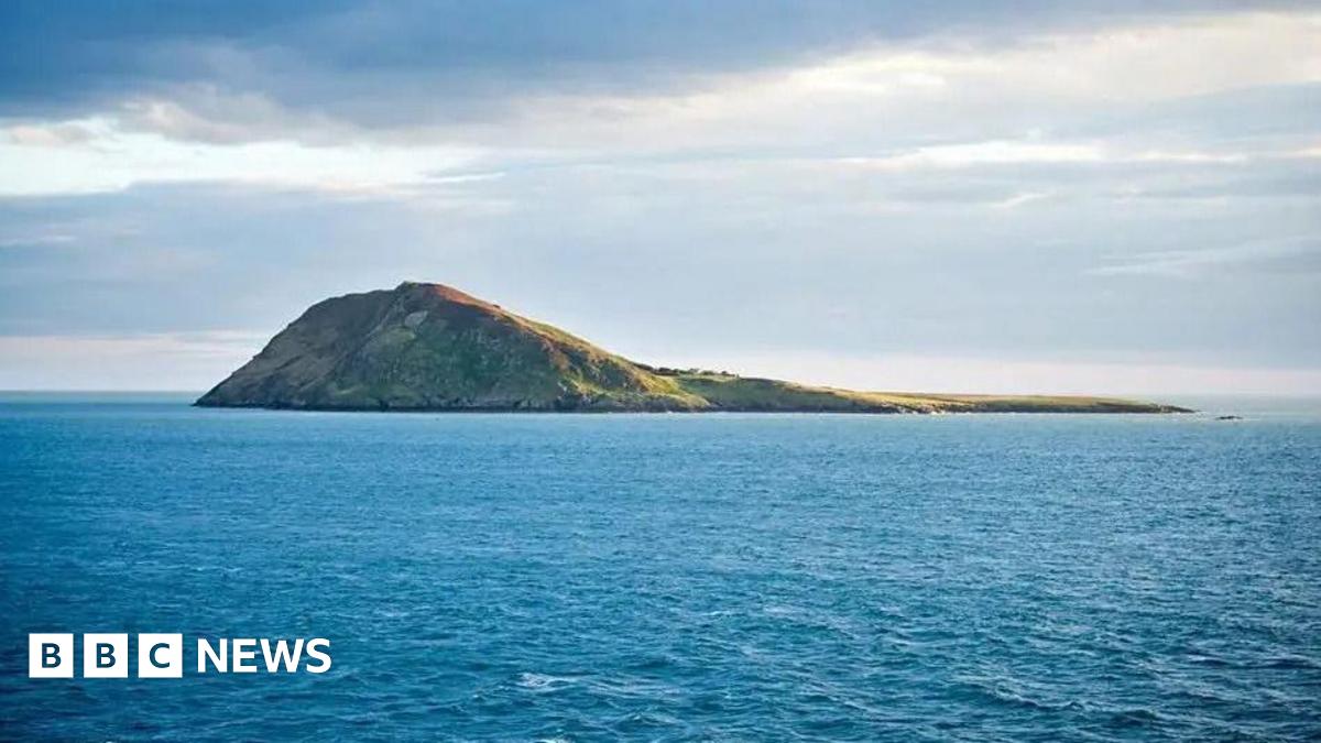 A rocky islet sits in the middle of the sea.