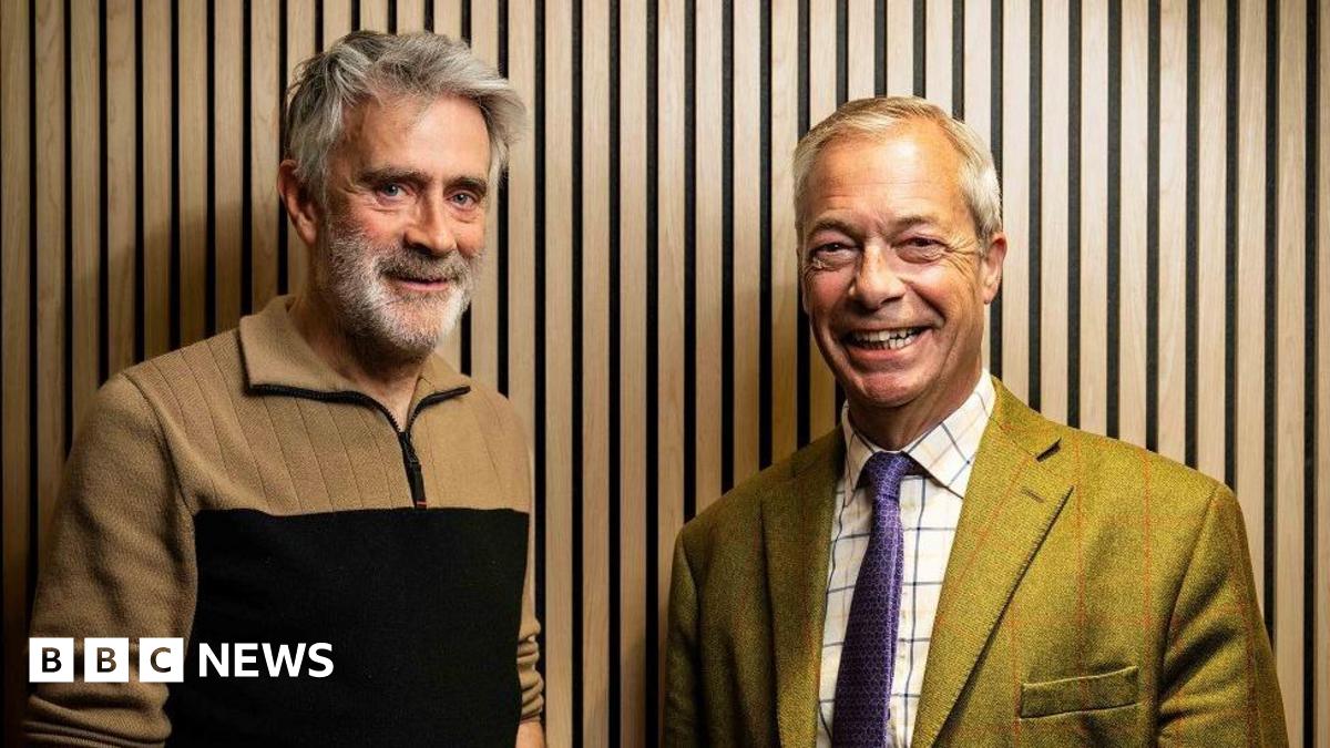 Christopher Harborne, left, wears a beige and black jumper. He has a full head of grey hair and a grey beard and bushy eyebrows. He stands next to Farage who is grinning. Farage is wearing a green suit and checked shirt and purple tie. 