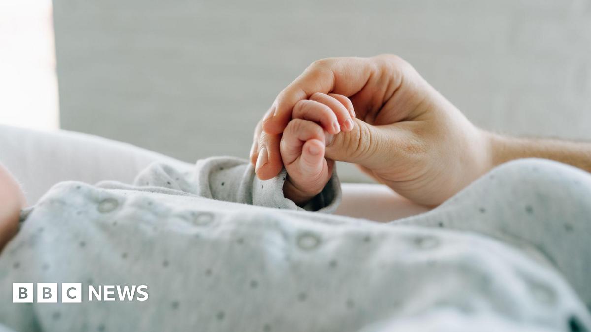 An adult hand holding a baby's hand