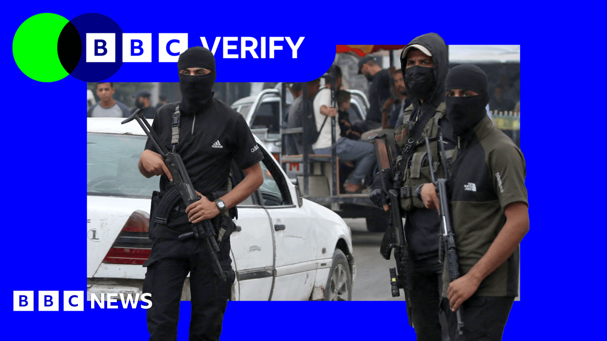 Three Hamas fighters stand guard in Gaza. They are wearing balaclavas and armed with assault rifles. 