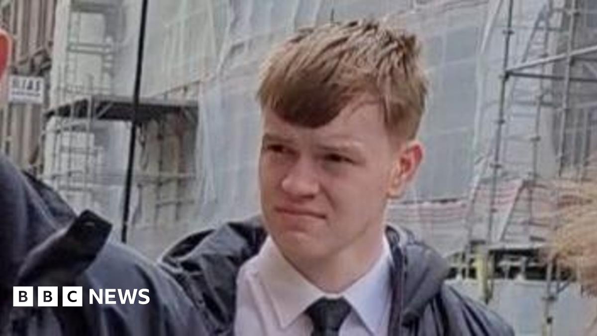 A red-headed teenager wearing a shirt and tie outside a court