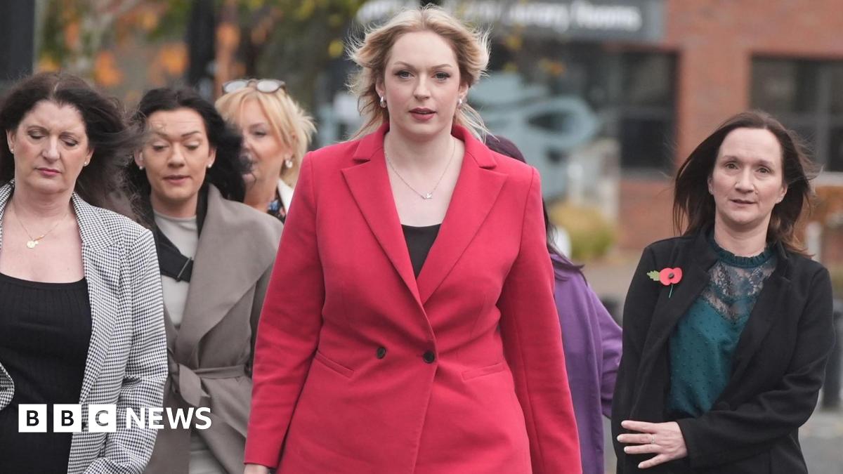 A group of women arrive at the tribunal office. At the head of the group is Bethany Hutchison, who has long blond hair and is wearing a red coat. Beside her are several smartly dressed women with long brown hair.