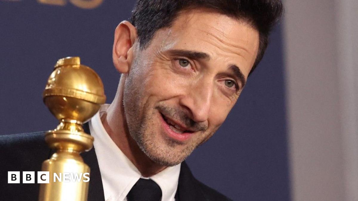 Adrien Brody holding up his the award for best actor in a drama, for The Brutalist
