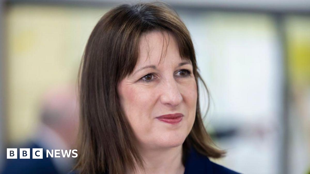Rachel Reeves dressed in a navy blue suit jacket gives a half-smile