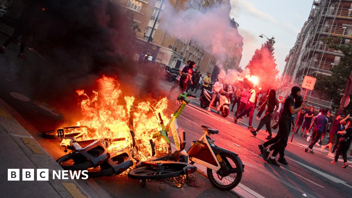 Rioters let off flares while e-bikes burn on a Paris street.