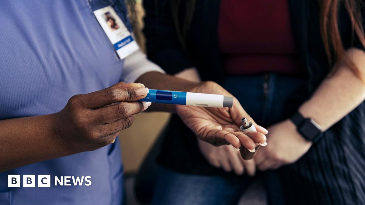 Close up stock image of a healthcare professional demonstrating to patient how to use a weight loss jab.