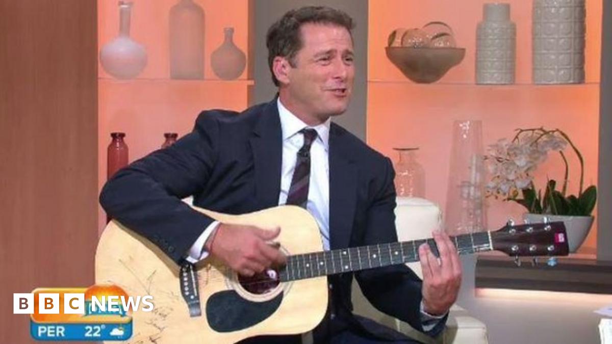 Karl Stefanovic wearing the blue suit, holding a guitar