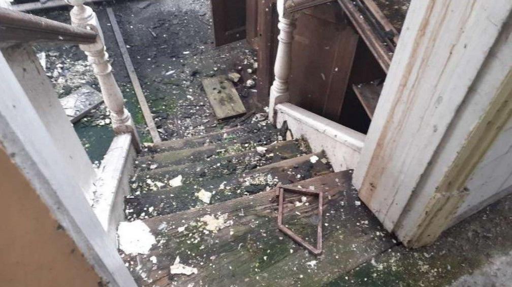 Debris scattered across a staircase which appears to be damaged.