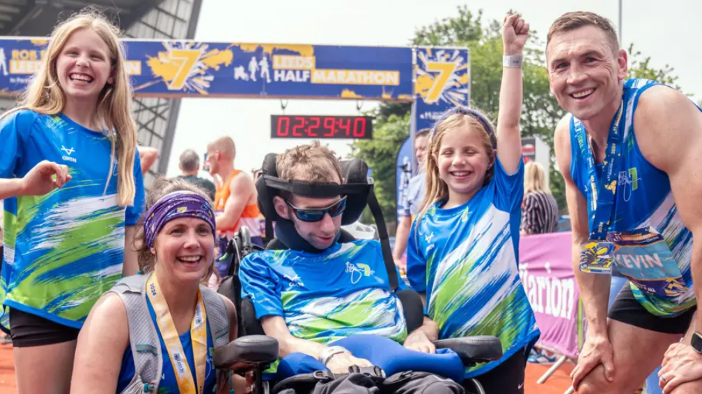 Rob Burrow in a wheelchair surrounded by his smiling wife, his two daughters and Sinfield at the Leeds Marathon