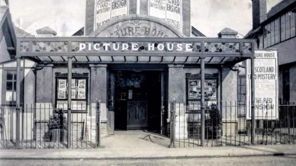 An old black and white image shows the front entrance of the Picture House