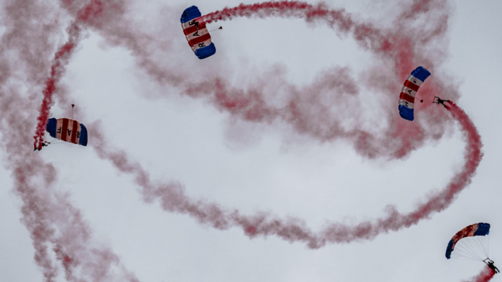 Sky divers falling with trails of red flares