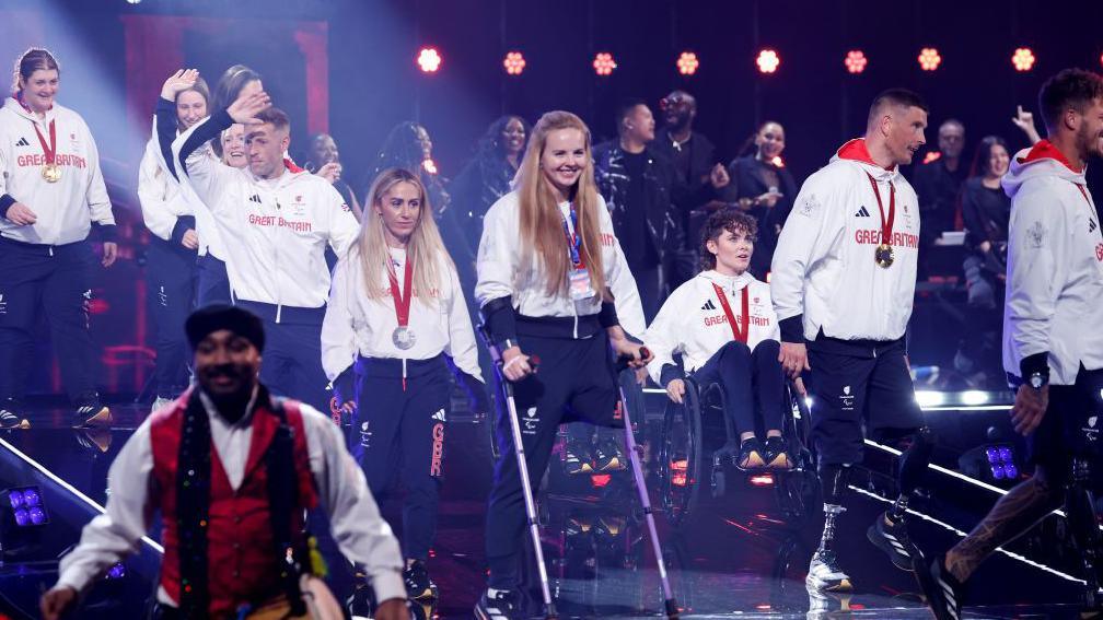 Some of the Team GB Paralympians on stage, wearing kit with medals around their necks