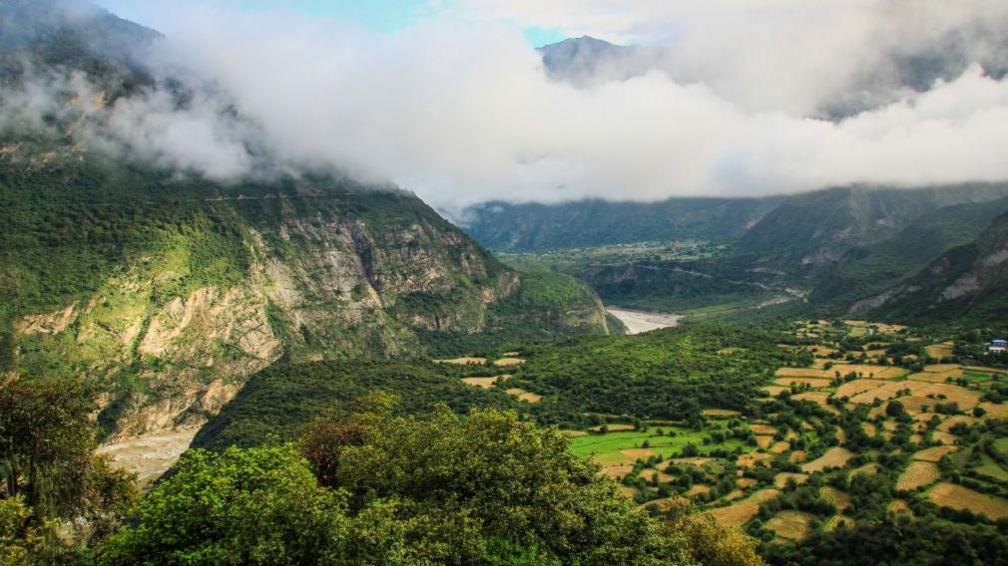 A view of Yarlung Zangbu Grand Canyon showing the eponymous river winding through a deep, wide and verdant canyon.