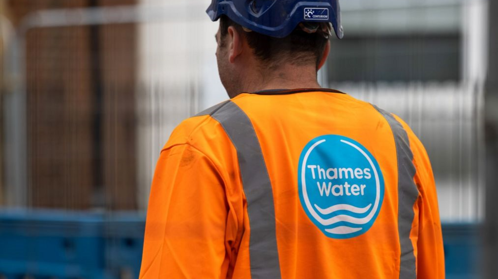 Man in fluorescent orange jacket with blue and white Thames Water logo on the back