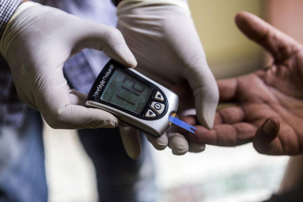 A health worker conducts a blood glucose test for a patient while during a free door-to-door screening programme.