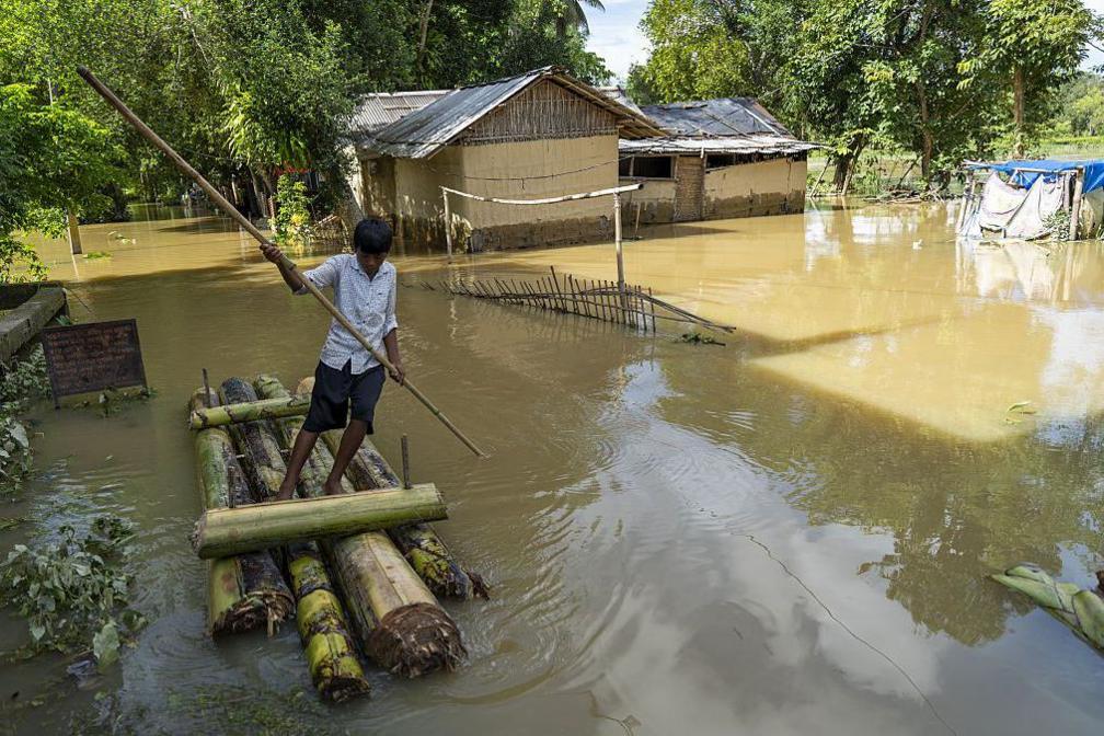 A boy uses a makeshift banana raft to navigate floodwaters past submerged homes in a flood-affected neighborhood, on July 22, 2026 in Jorhat, India. 