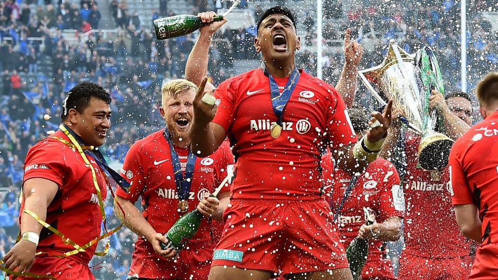 The champagne is sprayed as Saracens' players including Saracens' New Zealand born Australian lock Will Skelton celebrate their win on the field after the European Rugby Champions Cup final match between Leinster and Saracens at St James' Park